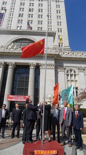 袁南生与关丽珍一同升起五星红旗。（美国《侨报》/张凯西 摄）